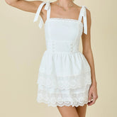 White lace dress with ribbon straps on a beige background